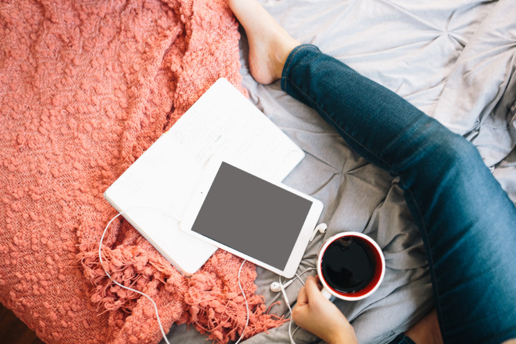 Person mit Laptop und Rechnungsprogramm sitzt auf dem Bett